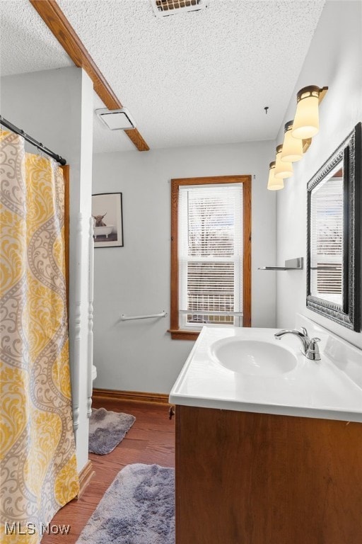 bathroom featuring toilet, a textured ceiling, wood finished floors, baseboards, and vanity