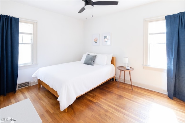 bedroom featuring a ceiling fan, baseboards, visible vents, and wood-type flooring