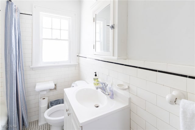 full bathroom featuring vanity, a shower with curtain, wainscoting, tile walls, and toilet