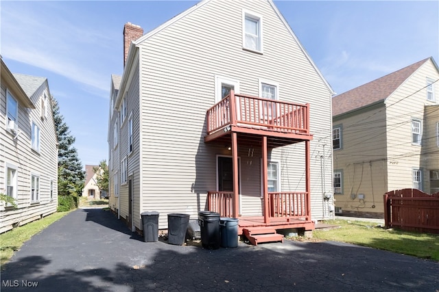 back of house with a balcony and a chimney