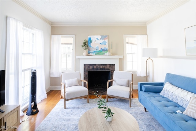 living room with a fireplace with flush hearth, ornamental molding, a textured ceiling, and wood finished floors