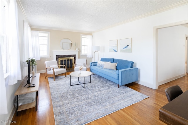 living room with a glass covered fireplace, crown molding, wood finished floors, and a textured ceiling