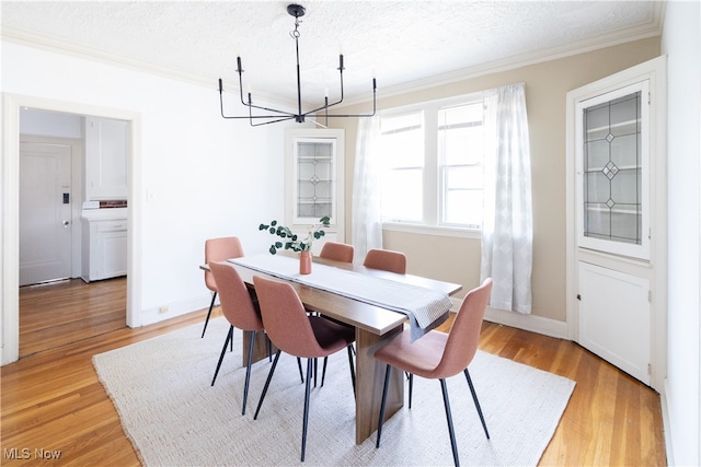 dining room with light wood-style flooring, a textured ceiling, washer / dryer, and ornamental molding