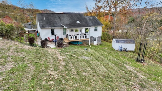 back of property with a shed, a yard, an outdoor structure, a deck, and a patio