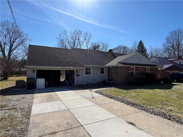 ranch-style home with brick siding, concrete driveway, a front yard, roof with shingles, and a garage