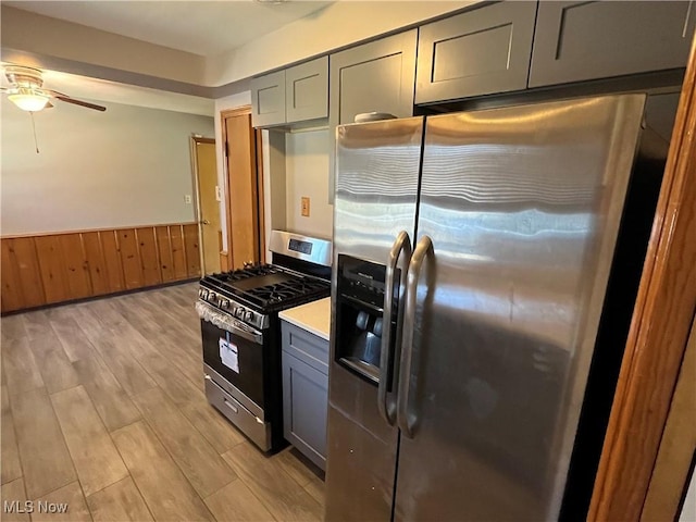 kitchen featuring light countertops, wainscoting, gray cabinets, light wood-style flooring, and stainless steel appliances