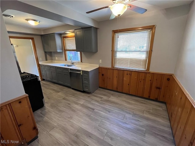 kitchen featuring gray cabinets, wainscoting, dishwasher, gas range, and a wealth of natural light