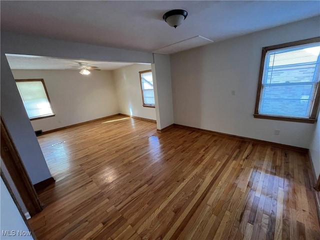 empty room featuring a ceiling fan, wood finished floors, and baseboards