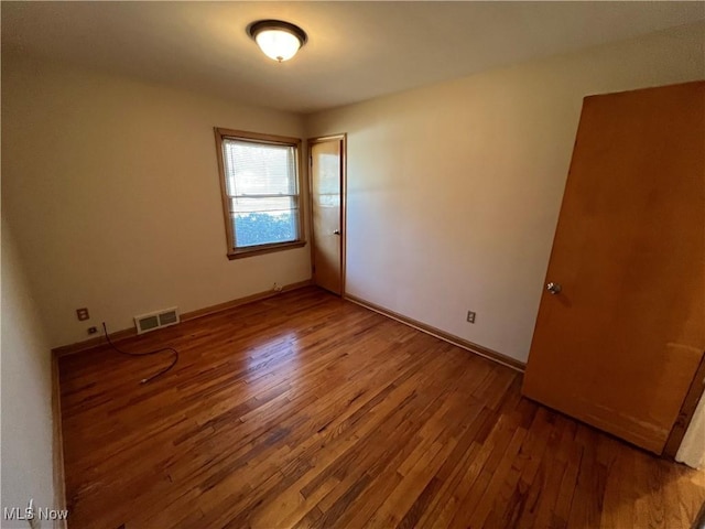 empty room featuring visible vents, baseboards, and hardwood / wood-style floors