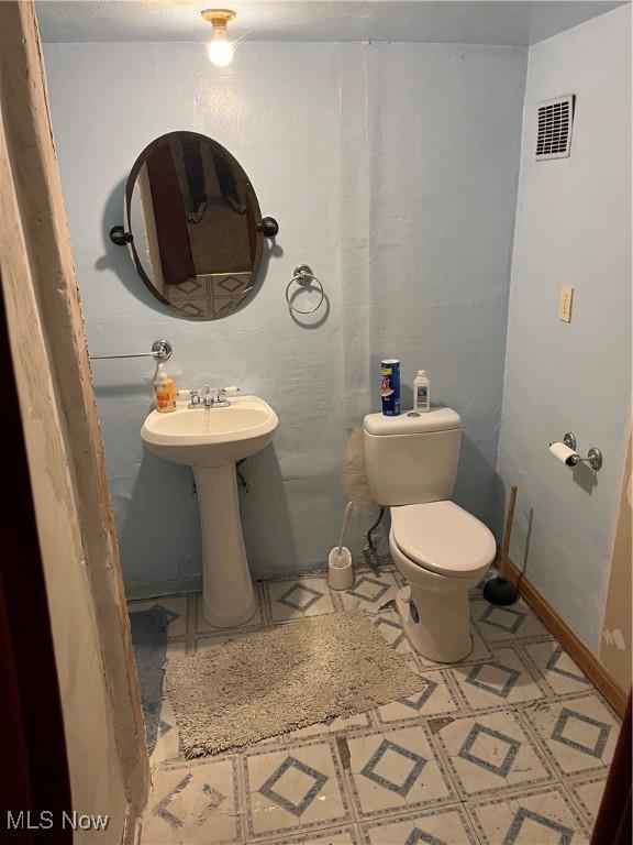 bathroom with visible vents, toilet, baseboards, and a sink