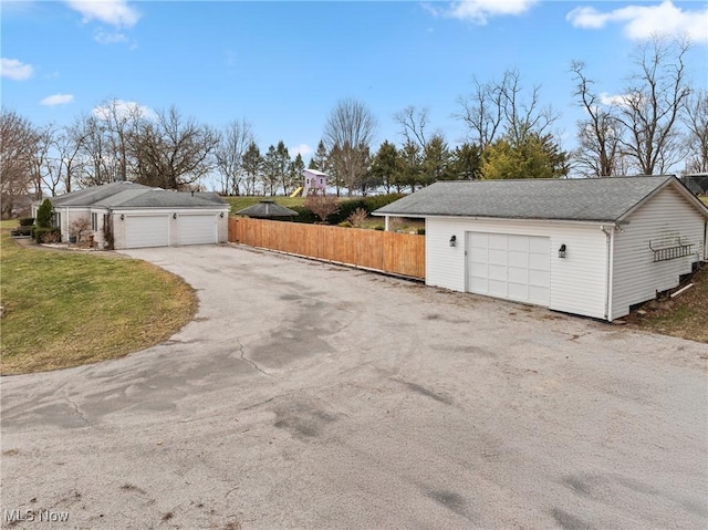 view of side of home with a yard, a detached garage, and fence