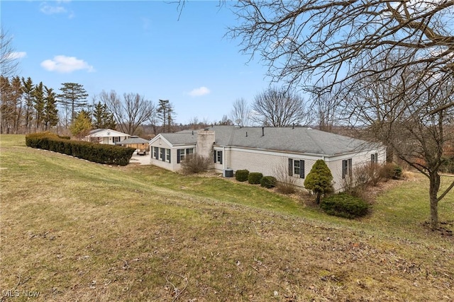 back of property with a chimney and a yard