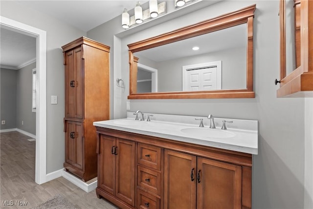 full bathroom with double vanity, wood finished floors, baseboards, and a sink