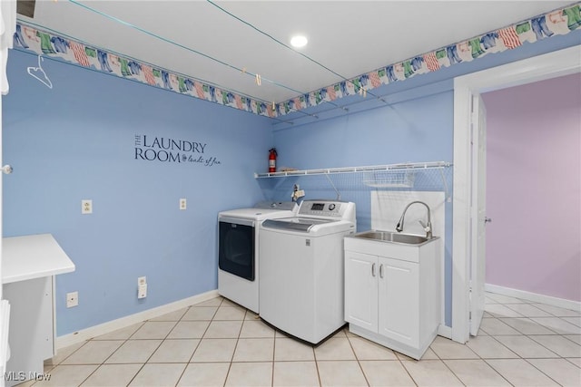 clothes washing area featuring washer and clothes dryer, light tile patterned floors, cabinet space, and a sink