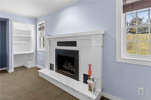 interior details with built in shelves, carpet flooring, crown molding, baseboards, and a brick fireplace