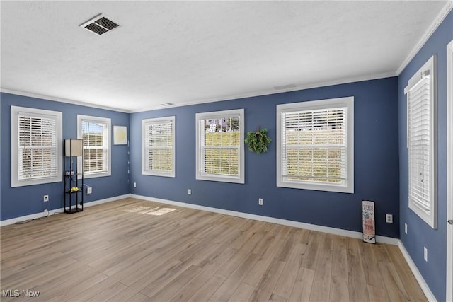 empty room with visible vents, crown molding, baseboards, and wood finished floors