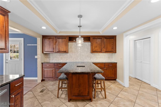 kitchen featuring a kitchen bar, ornamental molding, a tray ceiling, stainless steel dishwasher, and decorative backsplash