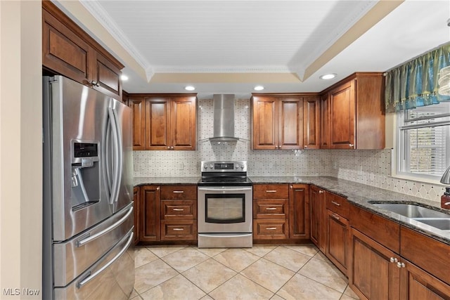 kitchen with a sink, stainless steel appliances, wall chimney exhaust hood, and a raised ceiling