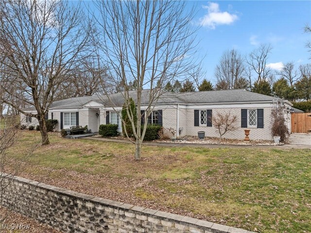 ranch-style house with a front yard, fence, and brick siding