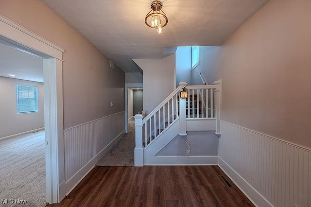 stairs with a wainscoted wall, visible vents, and wood finished floors