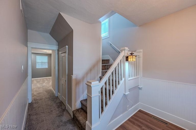 staircase featuring visible vents, wood finished floors, and a wainscoted wall