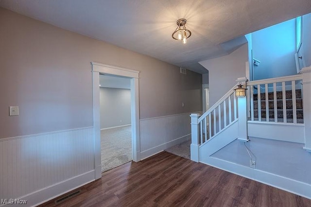 stairway with visible vents, wainscoting, and wood finished floors