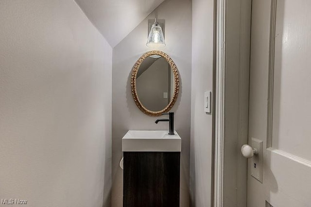half bathroom featuring vanity and lofted ceiling