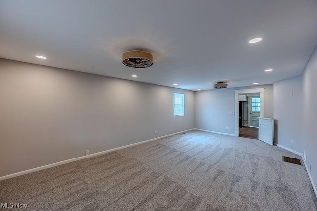 carpeted spare room featuring recessed lighting, baseboards, and visible vents