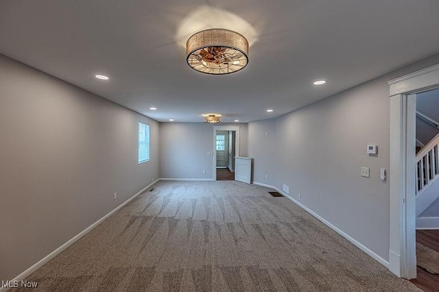 carpeted spare room featuring stairway, baseboards, and recessed lighting