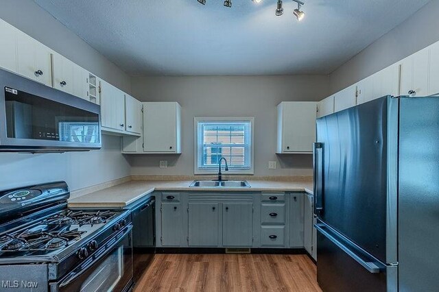 kitchen featuring a sink, light countertops, black appliances, and dark wood finished floors