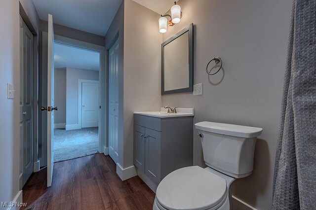 bathroom with toilet, baseboards, wood finished floors, and vanity