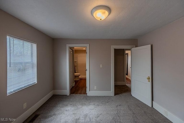 unfurnished bedroom featuring baseboards, carpet, and ensuite bathroom