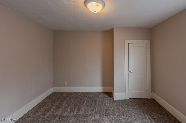 carpeted empty room featuring baseboards