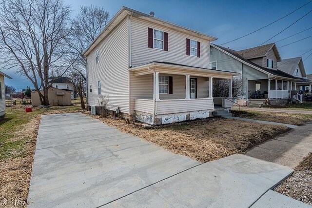american foursquare style home with an outdoor structure, a storage shed, central AC, and covered porch