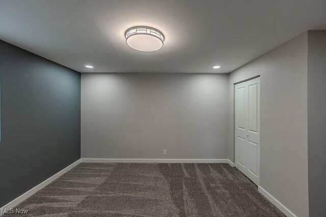 spare room featuring recessed lighting, baseboards, and dark colored carpet