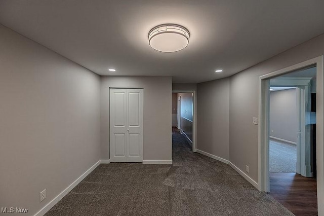empty room featuring recessed lighting, baseboards, and dark carpet