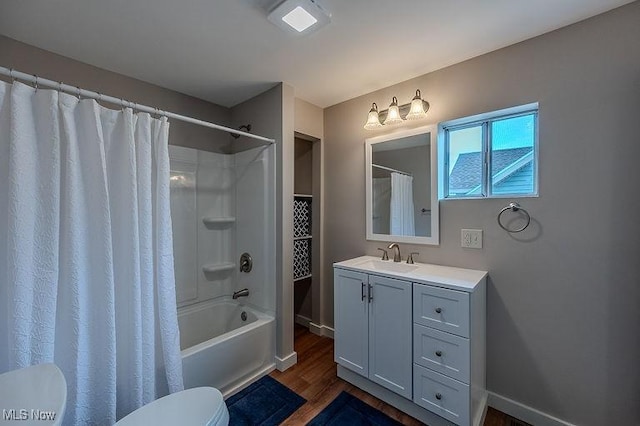 bathroom featuring vanity, toilet, baseboards, wood finished floors, and shower / tub combo