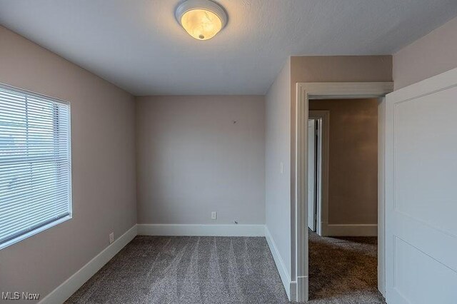 carpeted spare room featuring baseboards