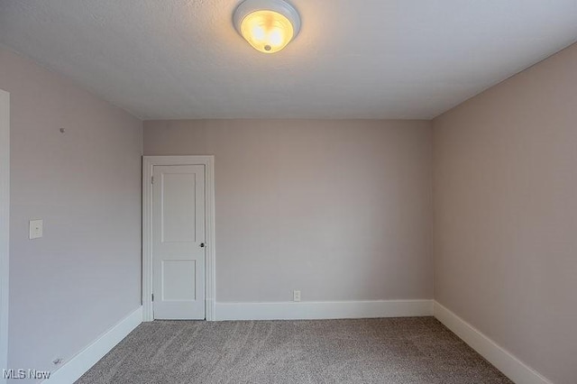 unfurnished room with carpet floors and baseboards