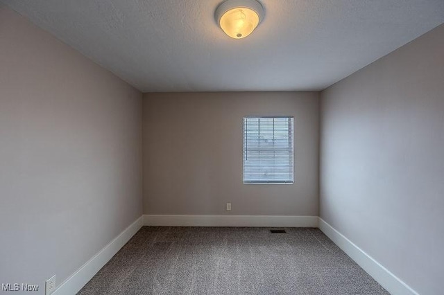 spare room featuring carpet floors, baseboards, and visible vents
