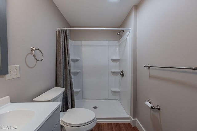 bathroom featuring a shower with curtain, wood finished floors, baseboards, vanity, and toilet