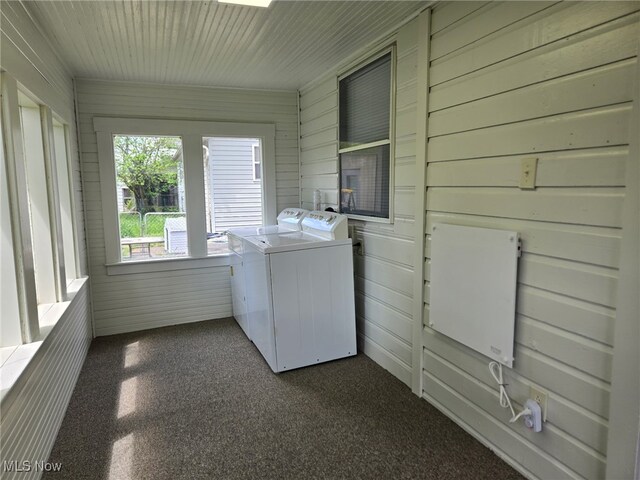 laundry area with independent washer and dryer, wooden walls, laundry area, and dark colored carpet