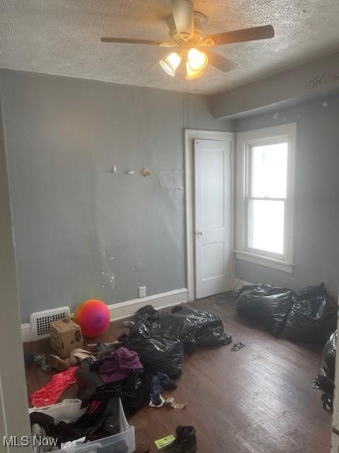 interior space with baseboards, wood finished floors, visible vents, and a textured ceiling