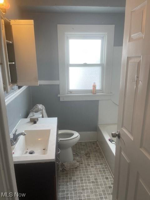 bathroom with toilet, a washtub, tile patterned flooring, baseboards, and vanity