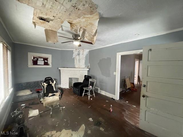 interior space featuring ornamental molding, a textured ceiling, a fireplace, baseboards, and ceiling fan