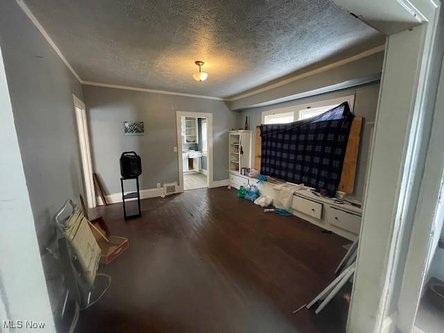 living room with visible vents, a textured ceiling, wood finished floors, crown molding, and baseboards