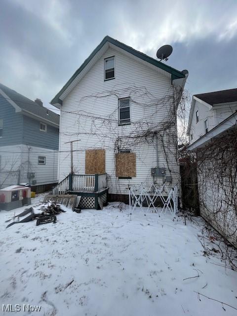 snow covered back of property with a wooden deck and central air condition unit