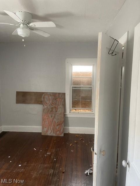 spare room featuring ceiling fan, baseboards, and wood-type flooring