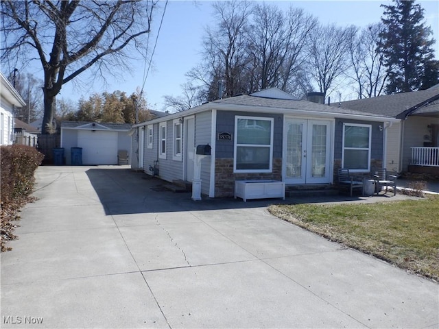 view of front of home with french doors, stone siding, an outdoor structure, and concrete driveway