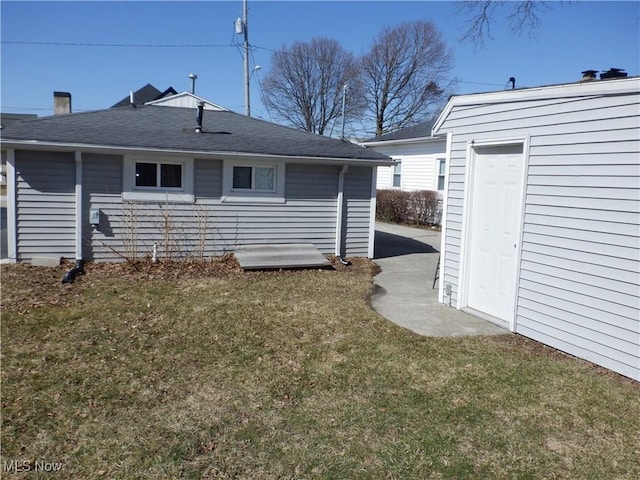 rear view of property with a lawn and a shingled roof